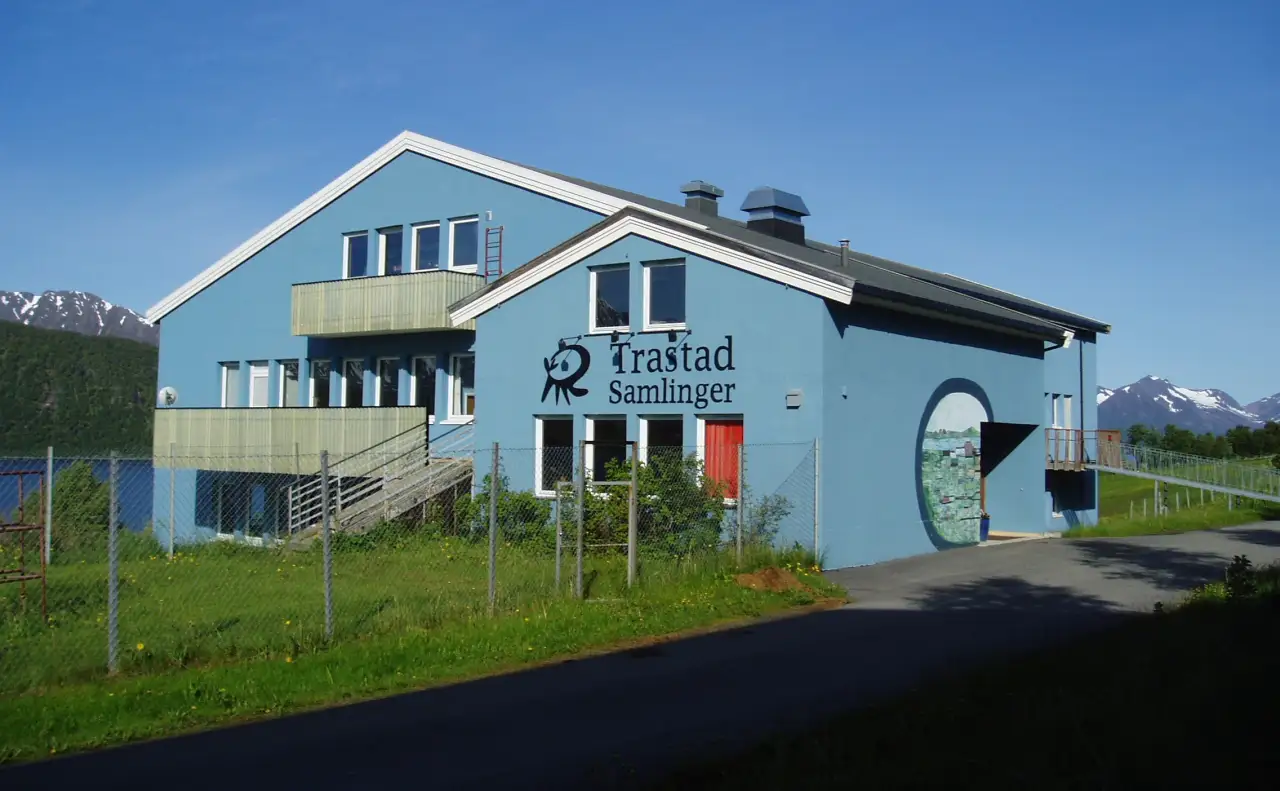 Trastad Samlinger museum ved Trastad Gård omgitt av grøntområde med fjell i bakgrunnen.