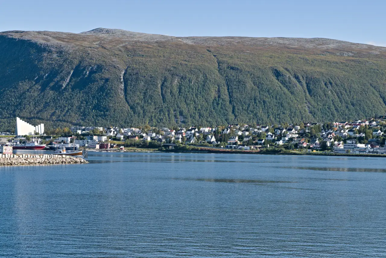 Tromsdalen sett fra sjøen med Arctic Cathedral og boligområder langs strandlinjen.