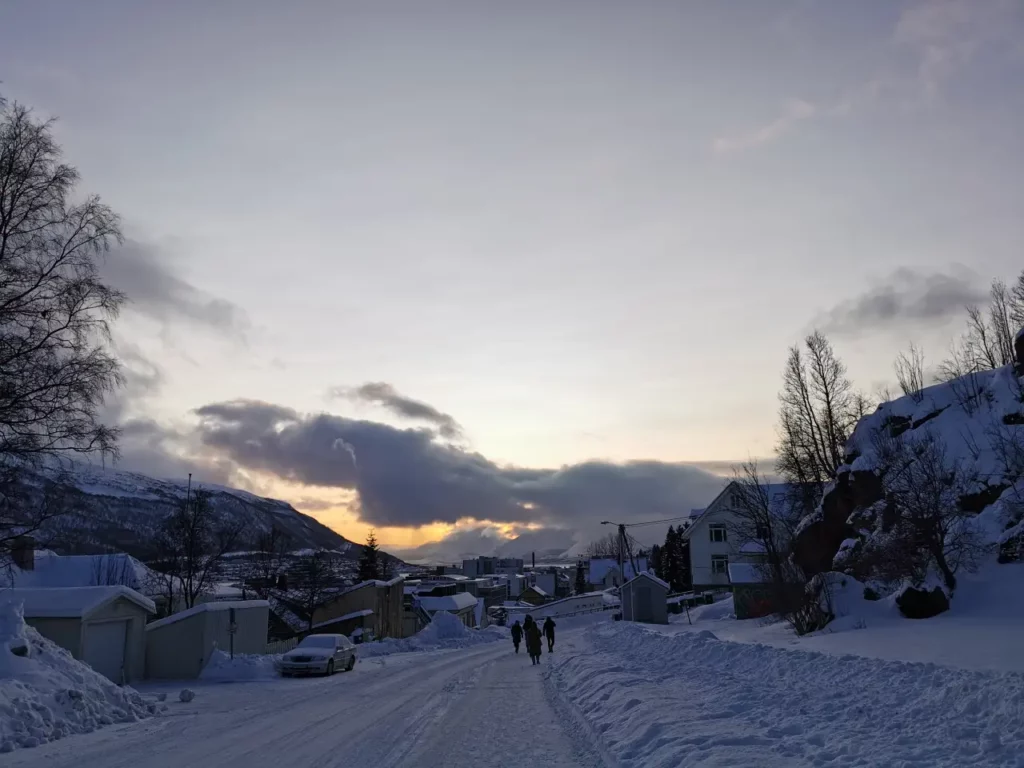 Vinterkveld på Dramsveien med folk som går mot Tromsø sentrum og fjell i bakgrunnen.