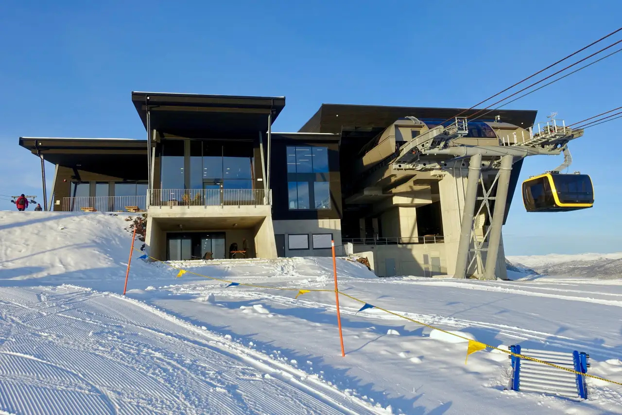 Toppstasjonen til Voss Gondol på Hangurstoppen med snøkledde løyper og gondolkabin som ankommer frå dalen.