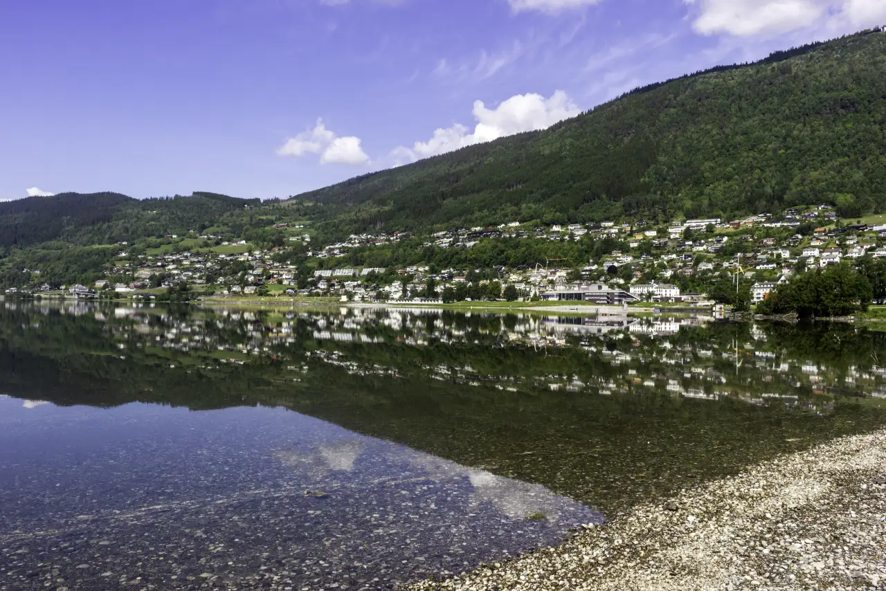 Vossevangen speglar seg i det stille Vangsvatnet med bustader og grønkledde dalsider rundt.