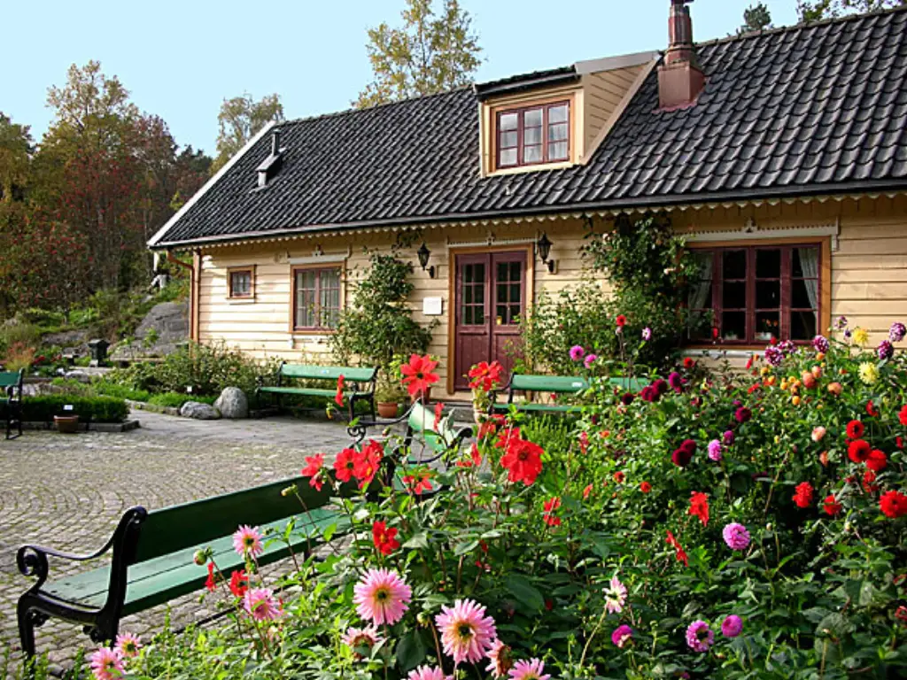 Blondehuset i Arboretet med dahliablomster og hage foran bygningen.