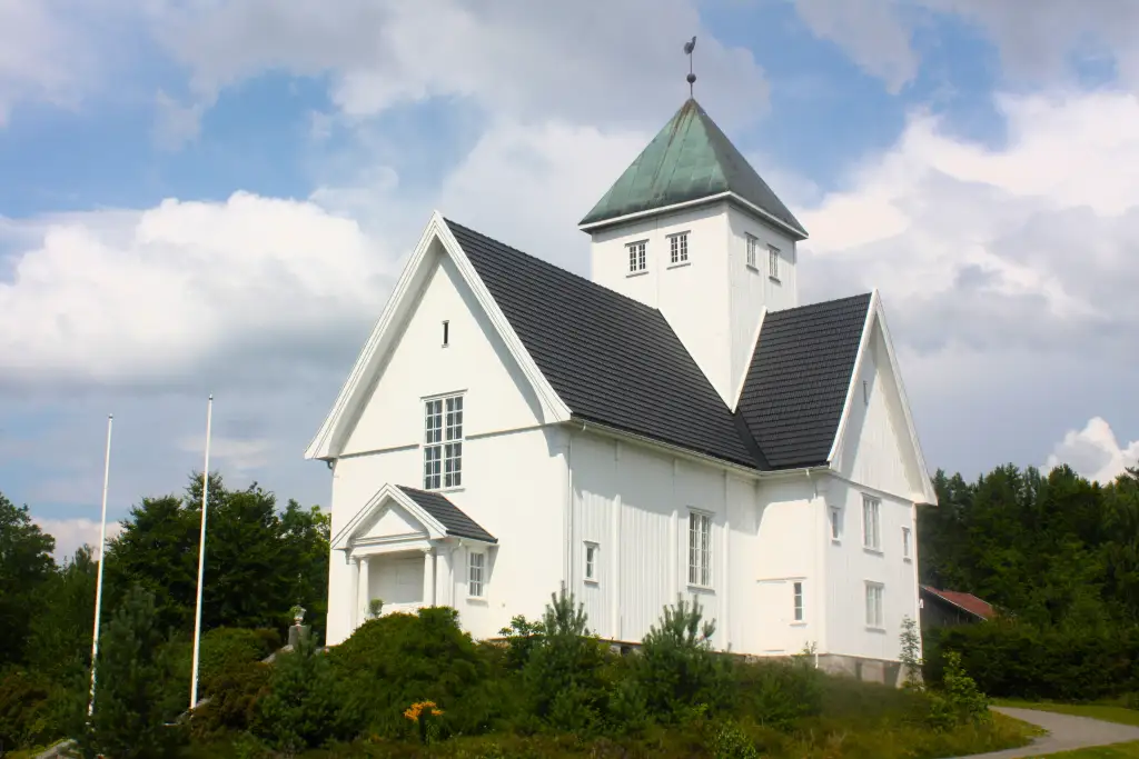 Eidsfoss kirke i Holmestrand hvitmalt trekirke med tårn i grønt landskap.