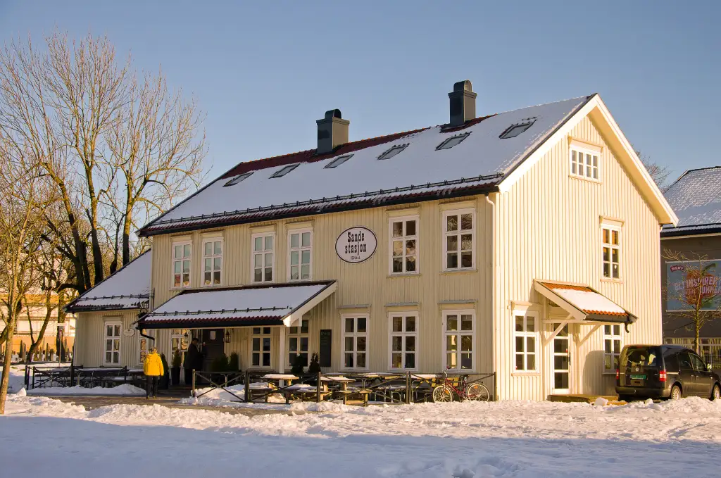 Gamle Sande stasjon i Sande med lys trebygning snø og vinterlys.