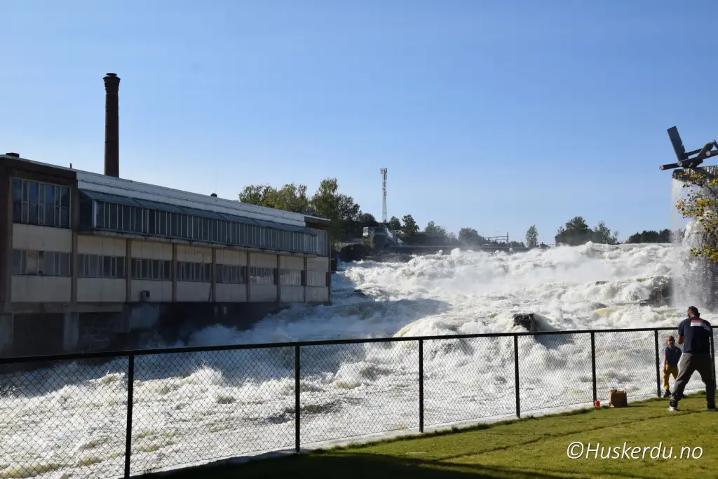 Hønefossen i Hønefoss med kraftig vannføring og besøkende langs gjerdet.