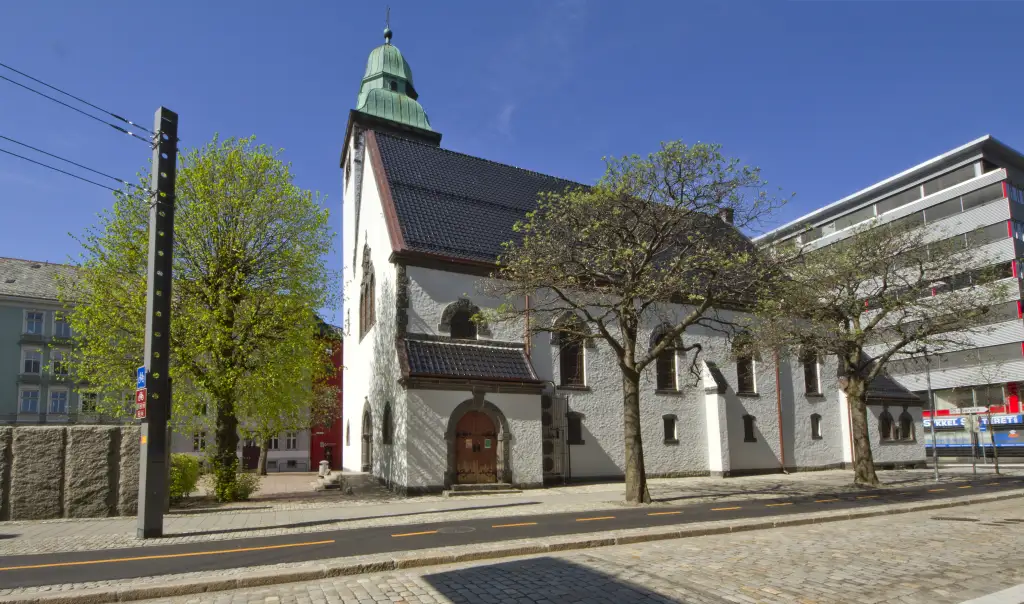 Nygård kirke med hvite murvegger og tårn sett fra gaten i Bergen.