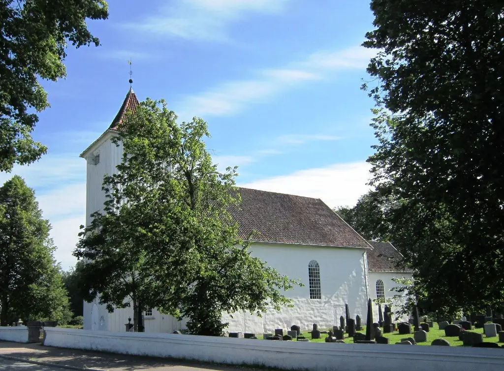 Sande kirke i Vestfold hvit steinkirke omgitt av kirkegård og grønt landskap.