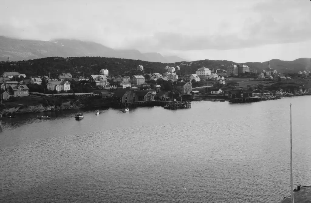 Sandnessjøen ved sjøen med brygger og husrekker i eldre oversiktsbilde