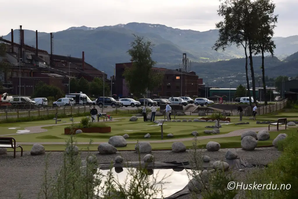 Minigolfbane ved Andedammen i Sauda med mennesker i spill og fjell i bakgrunnen