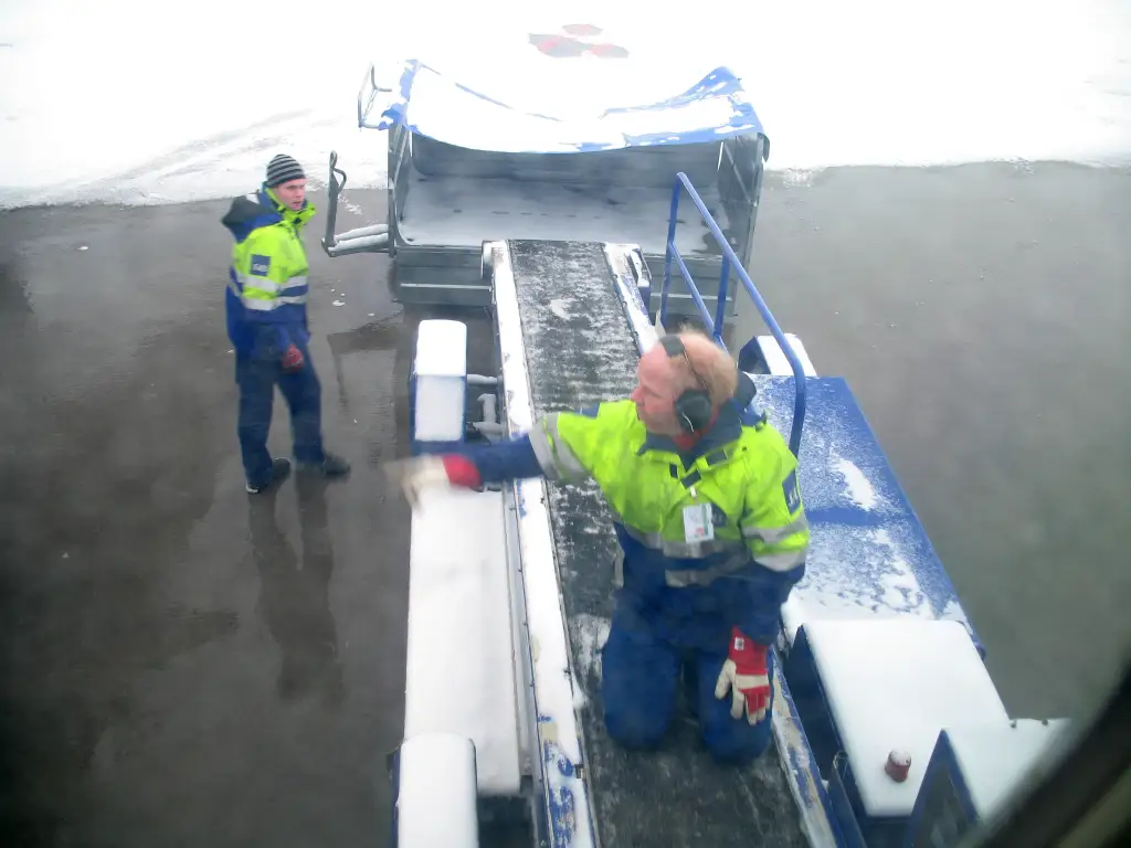 Bakketjenester som håndterer bagasje på Oslo lufthavn Gardermoen under vinterforhold.