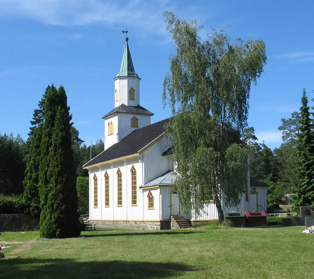 Færvik kirke på Tromøy med hvitmalt trekirke og tårn omgitt av grønt kirkegårdsområde.