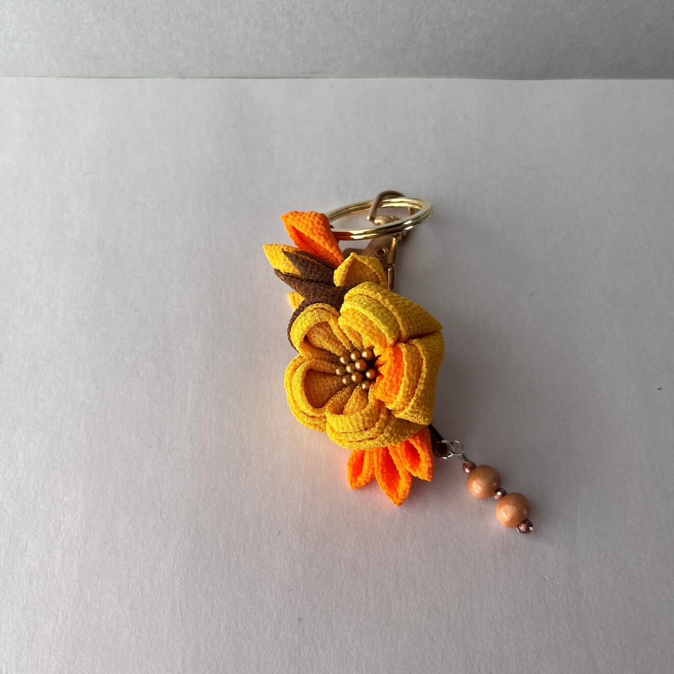 つまみ細工 バッグチャーム｜鬱金×柿色×橙色×落葉色 ゴールドヘップとウッドビーズ