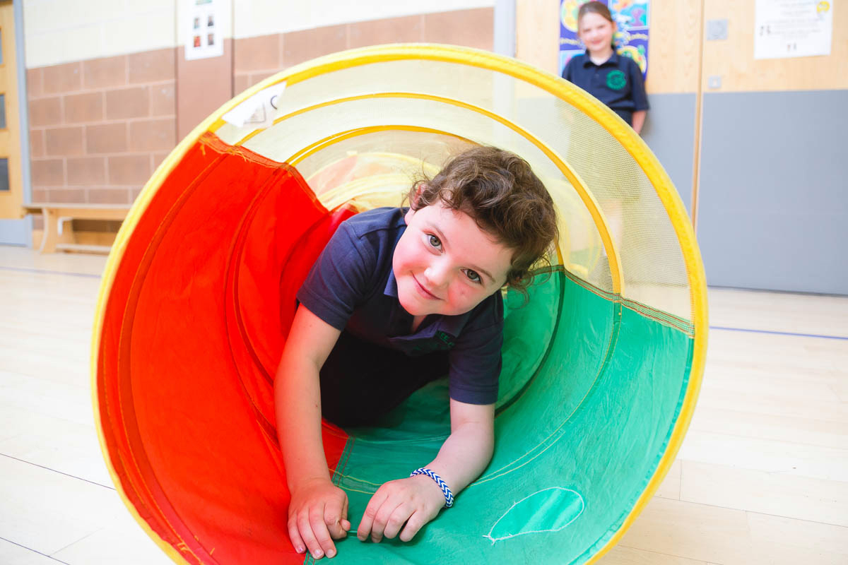 Young child crawling through colourful play tunnel