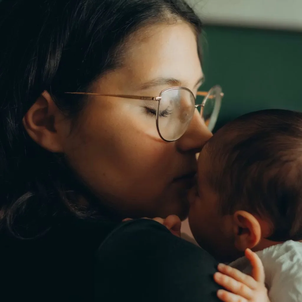 Woman kissing a baby, sharper detail after upscaling