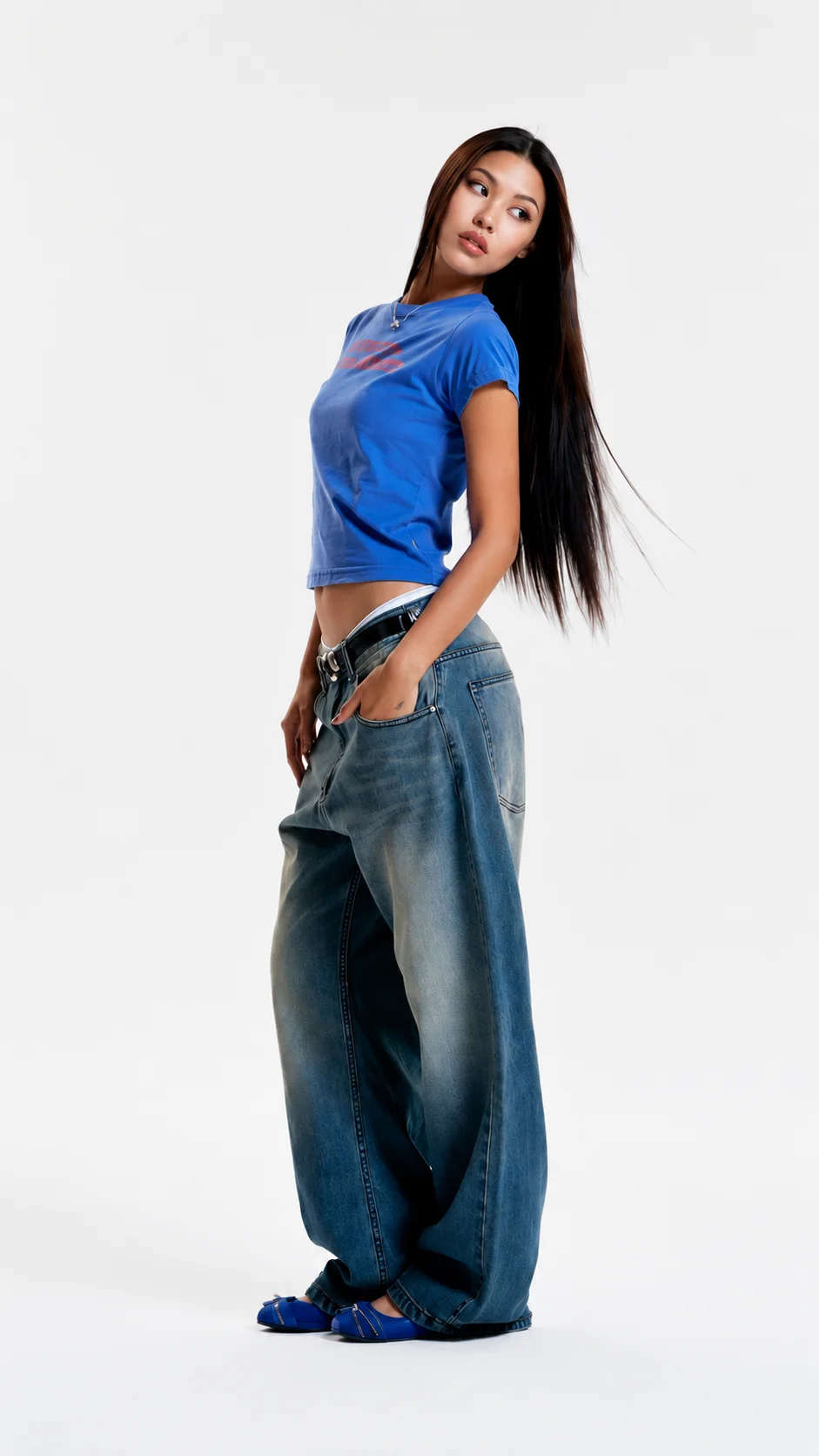 Model in a blue tee, wide-leg jeans, and blue flats, photographed in a studio