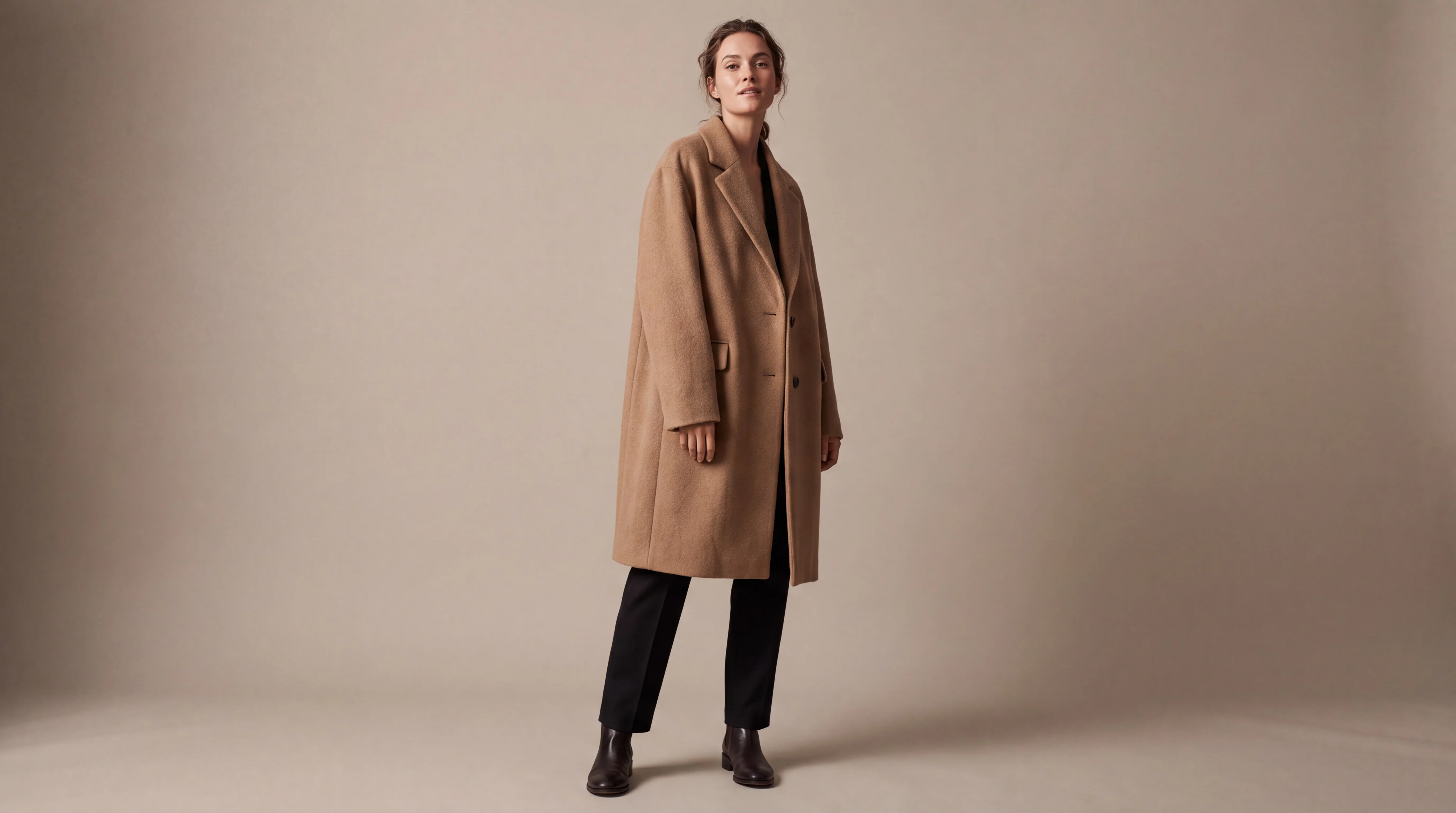 A model in a camel wool overcoat against a beige studio backdrop