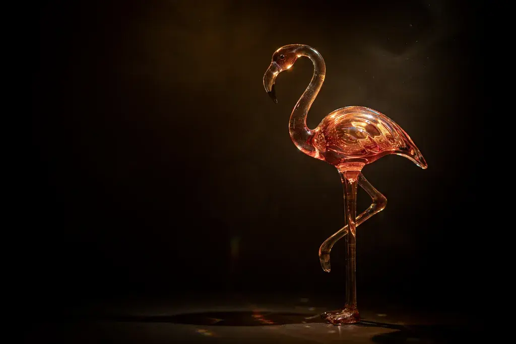 Iridescent glass flamingo sculpture lit in warm amber and rose gold tones