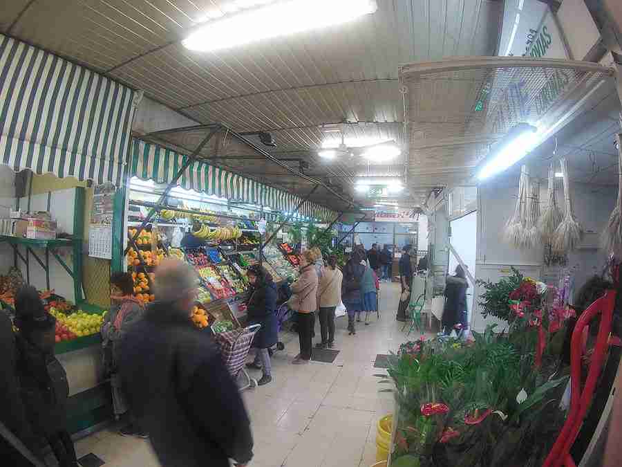 Vemos un pasillo del mercado "Las Palmeritas" de Sevilla, con plantas y vegetales en oferta.