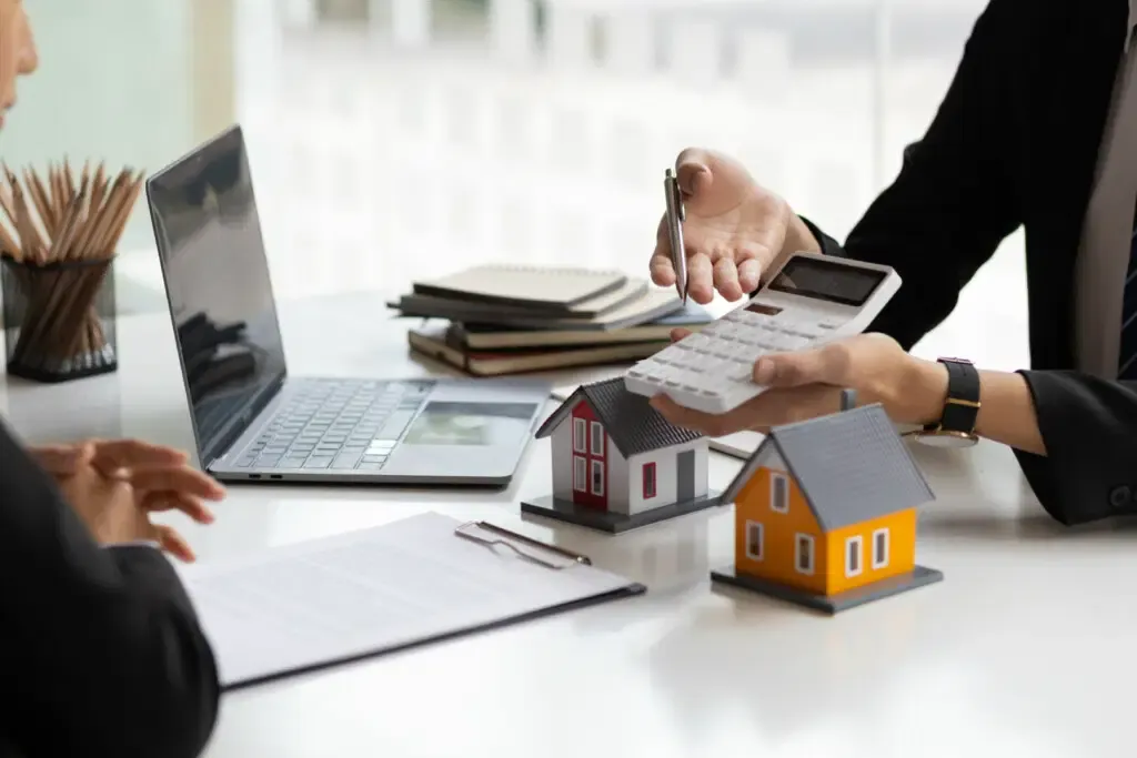 Ordinateur, mains, petites maisons et calculatrice