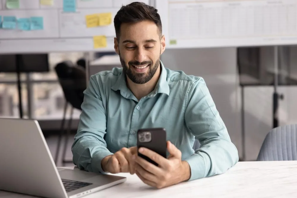 Persona pagando con una tarjeta de crédito digital acercando el celular a un terminal