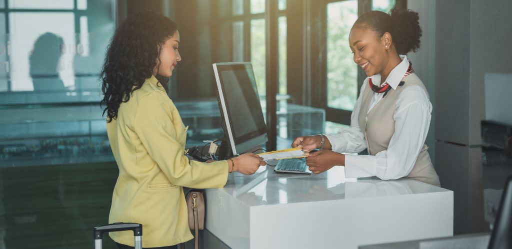 Trabajadora asesorando a turista en aeropuerto. 