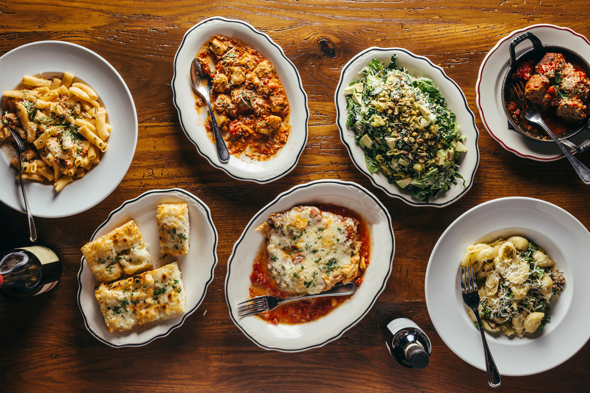 overhead photo of a variety of dishes from the catering menu including rigatoni, meatballs and garlic bread