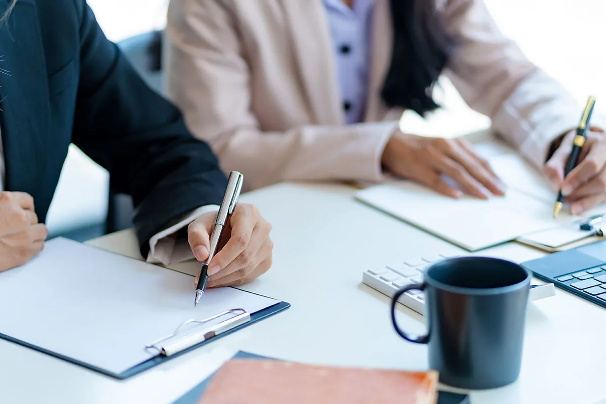 Two franchise compliance officers are drafting out documentation.
