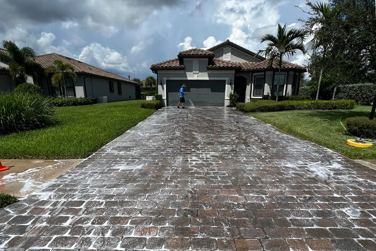 A pressure washing tech cleaning a paved driveway.