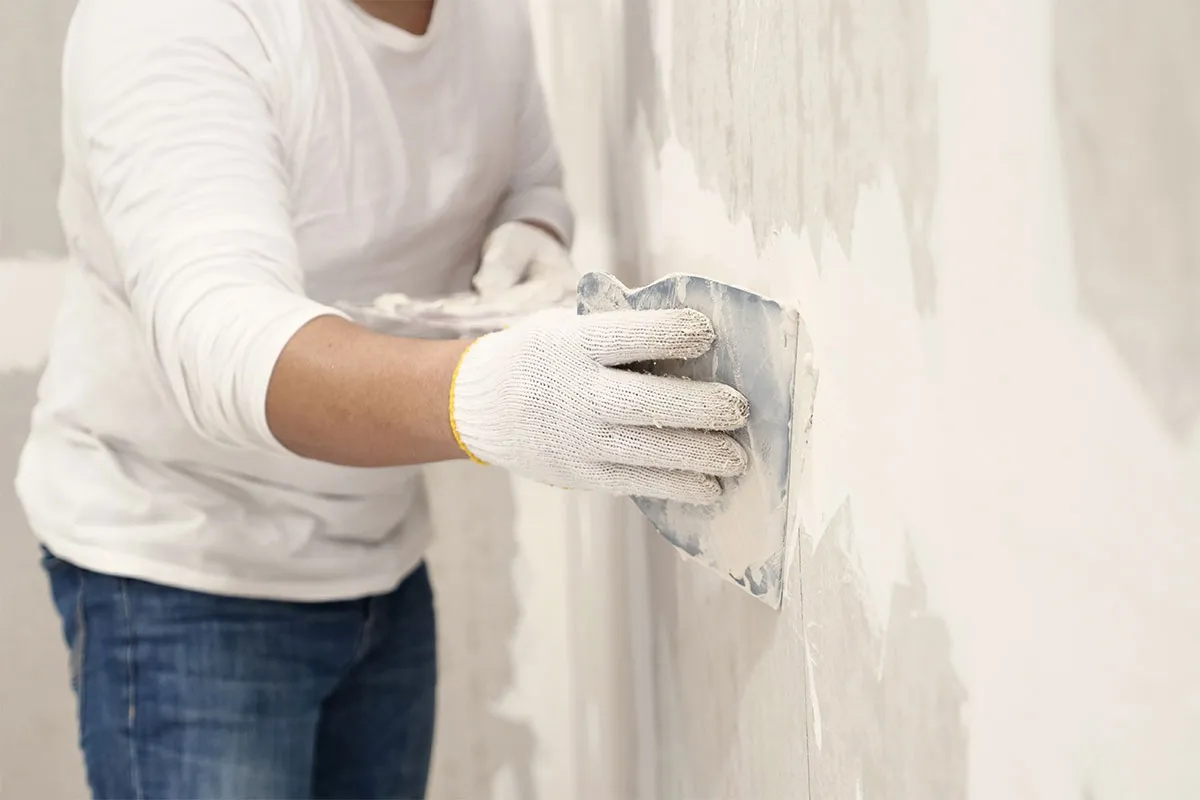 Handyman providing plastering in a home.