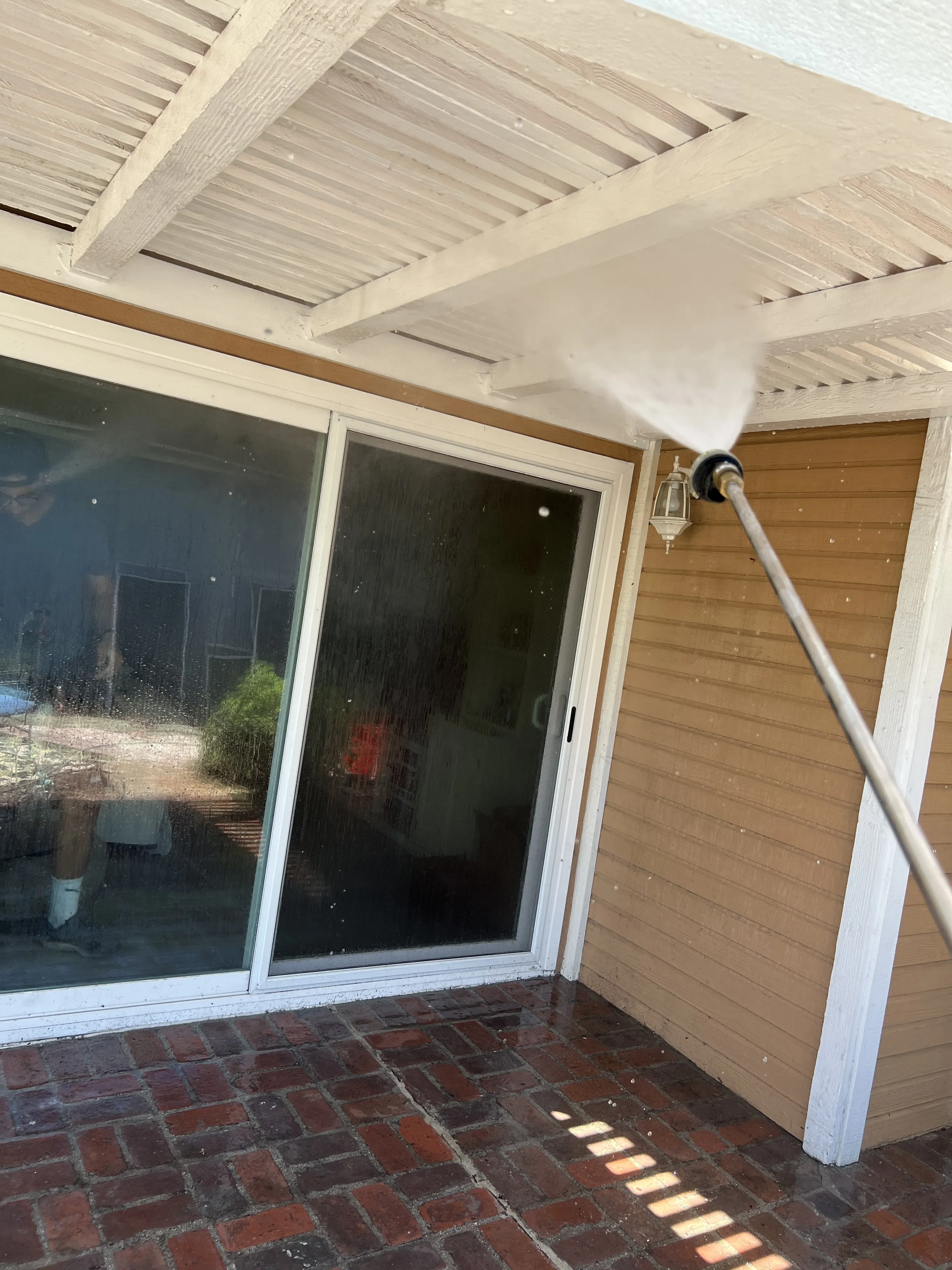 Professional house washing in Riverside, CA using low pressure to wash vinyl siding.