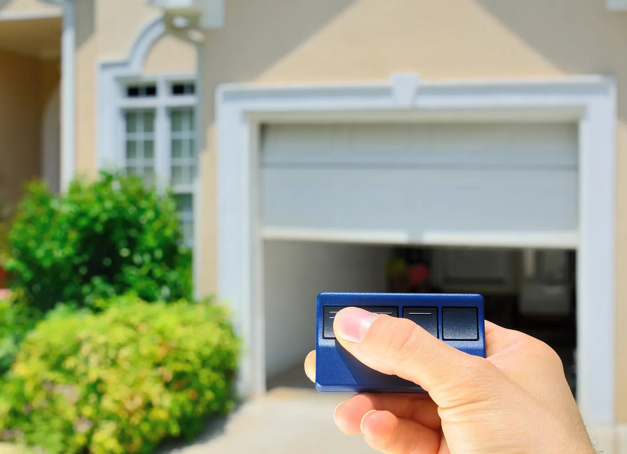 A person using their garage door opener to open their garage door.