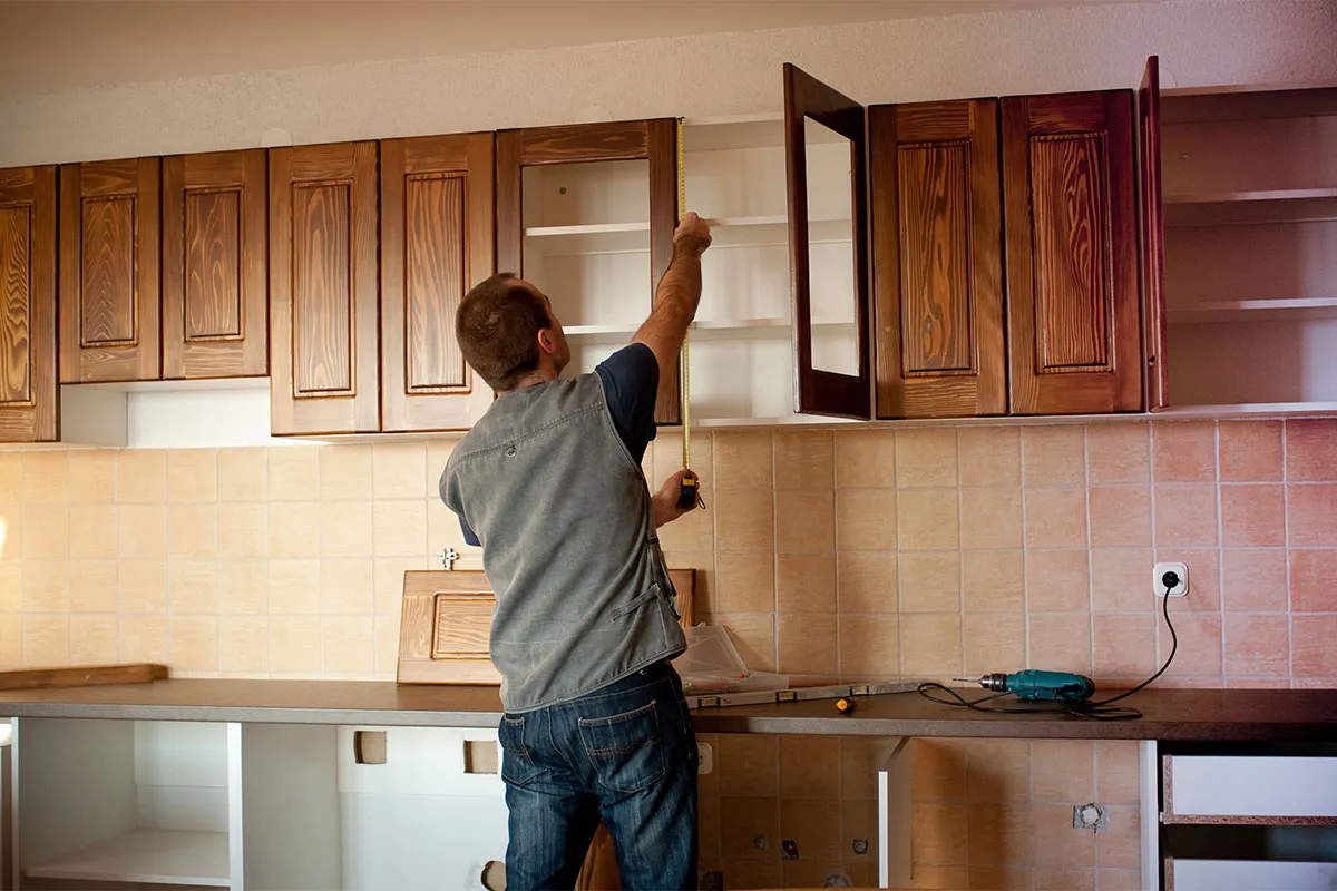 A professional installing new kitchen cabinets during a home remodel project.