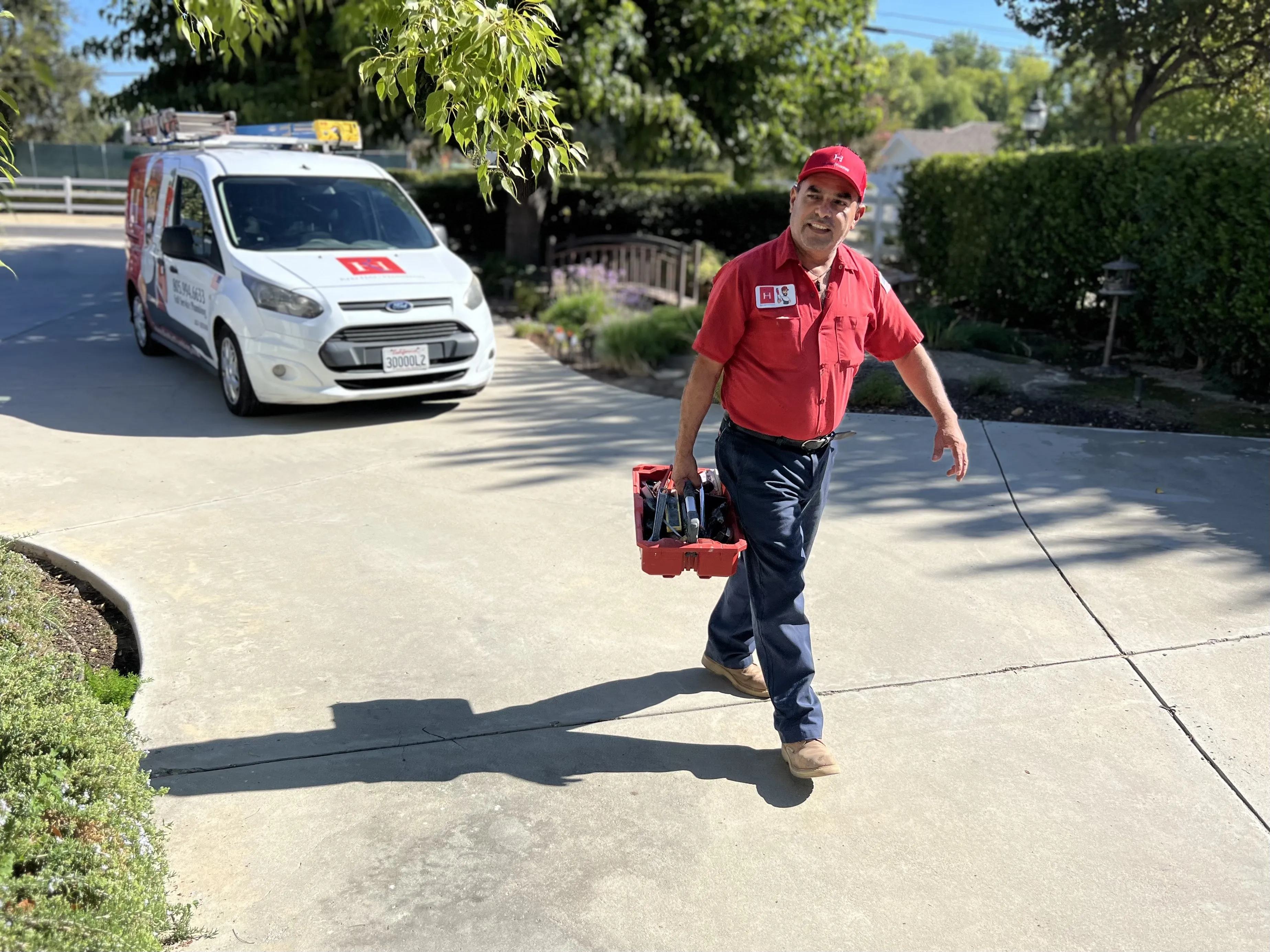 Red Hat Plumbing team member walking up a customer's driveway in Studio City.