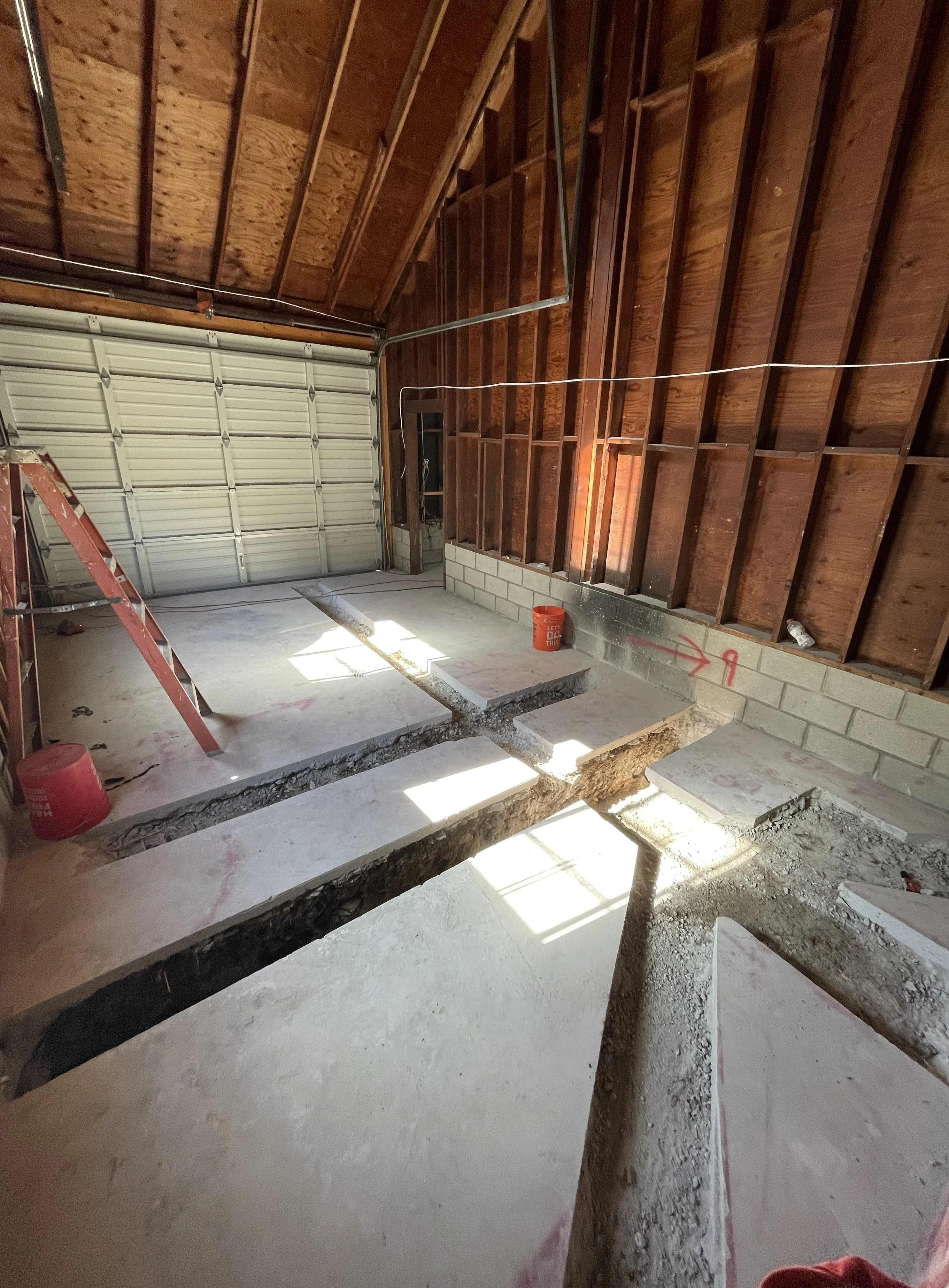 Garage with exposed foundation trench for plumbing repair and pipe replacement.