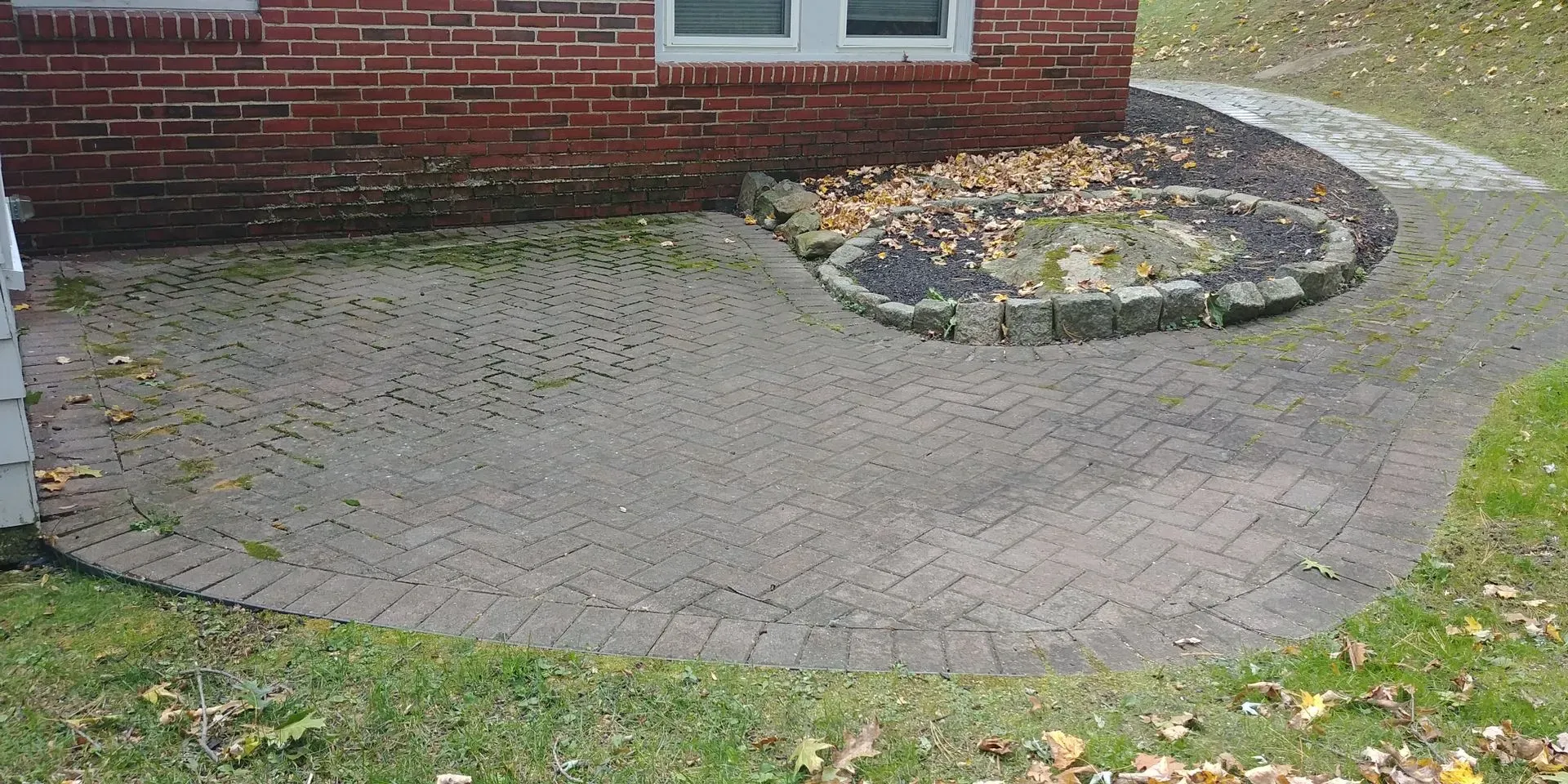 Technician pressure washing a concrete walkway in Methuen MA, removing built-up dirt, mold, and algae for improved safety and appearance.