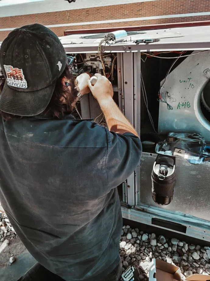 American Servicers technician fixing a HVAC system.