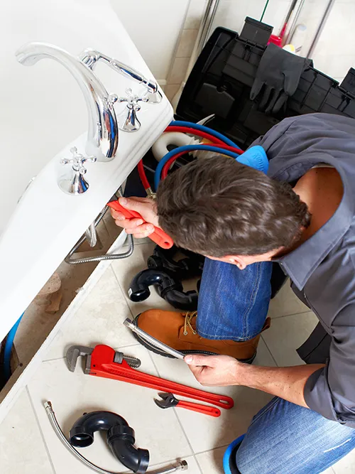 Professional plumbing service with plumber fixing pipe under a sink in Sugar Land, TX.