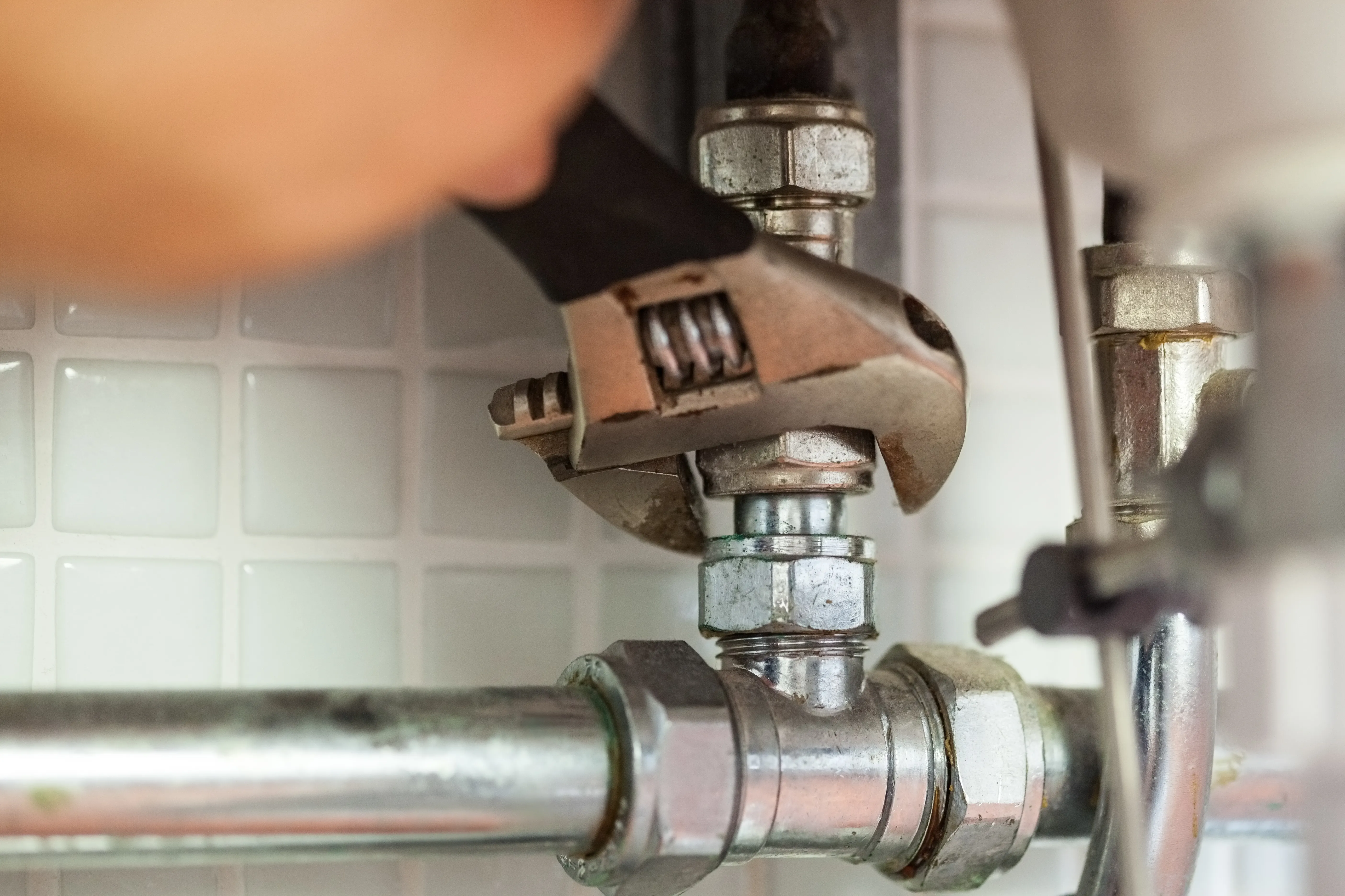 A plumber repairing a pipe under a kitchen sink.