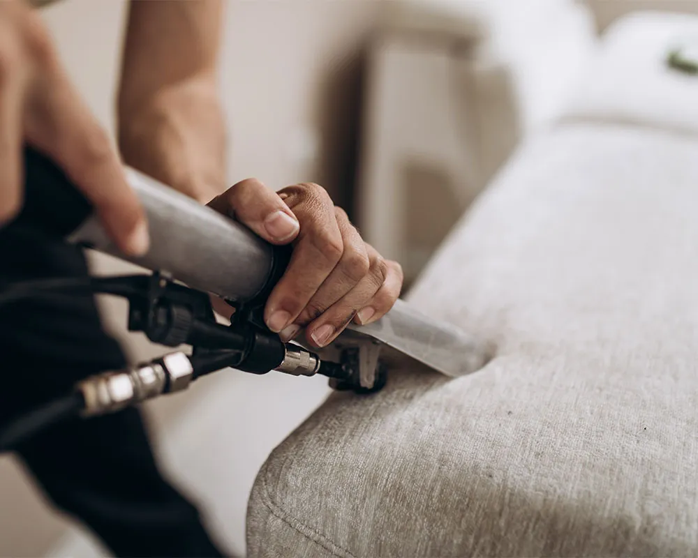 A vacuum cleaning a sofa.