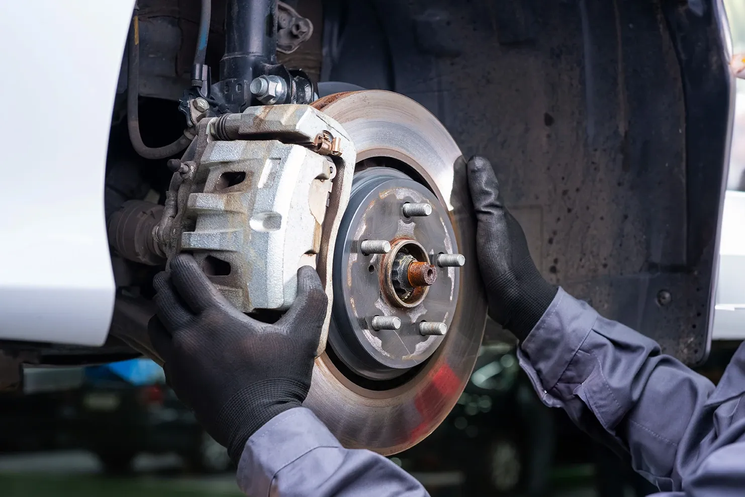Mobile auto repair technician installing new brake pads on a car in Porter, TX.