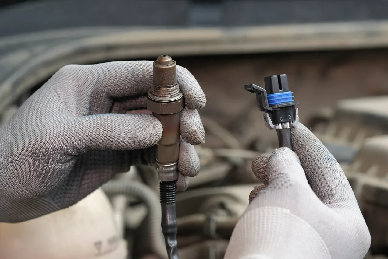 A mobile technician diagnosing and repairing a car sensor in Houston, TX.