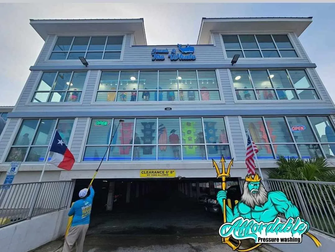 Technician cleaning large commercial windows with a squeegee and eco-friendly solution in a Hidalgo county building