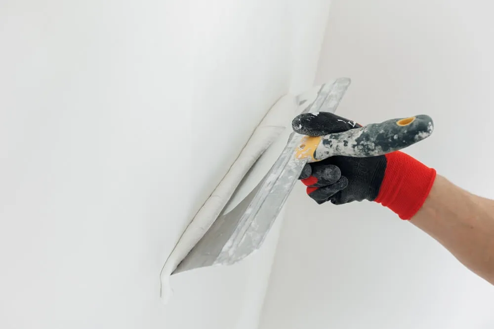 Professional repairing drywall holes and prepping for exterior painting