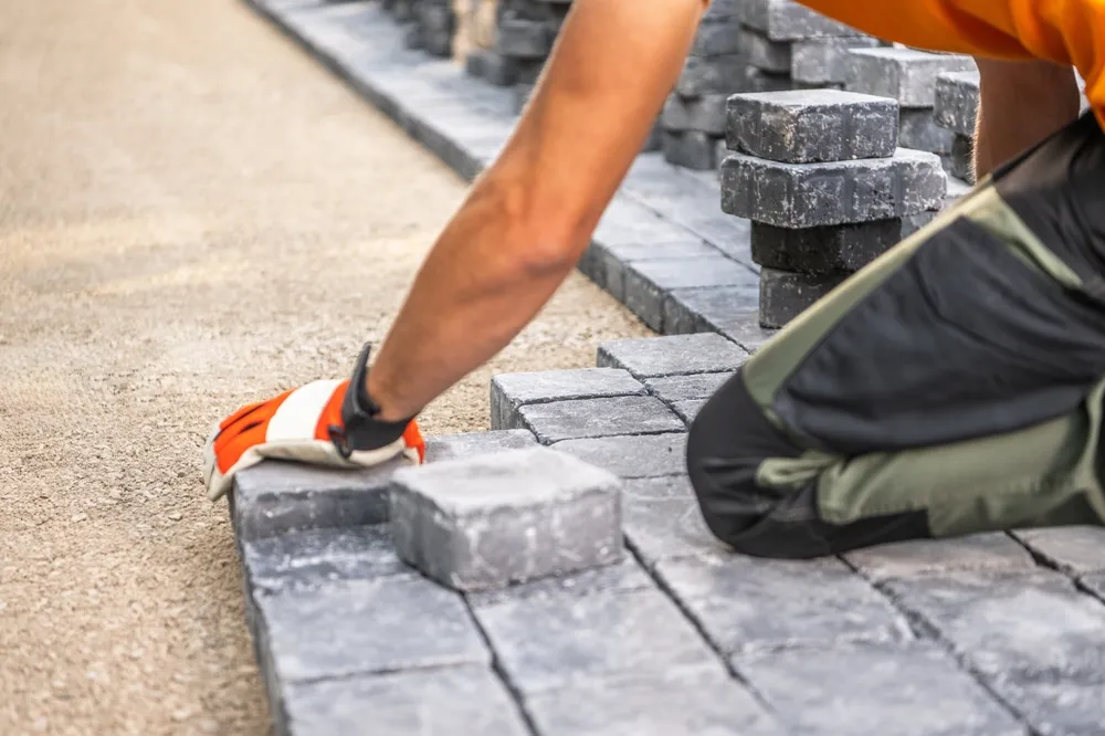 A landscaping services professional installs paving blocks in a front yard as part of seasonal services in tarrant county as part of landscape maintenance to add color for a better overall rating offered by a locally owned business for landscaping arlington.
