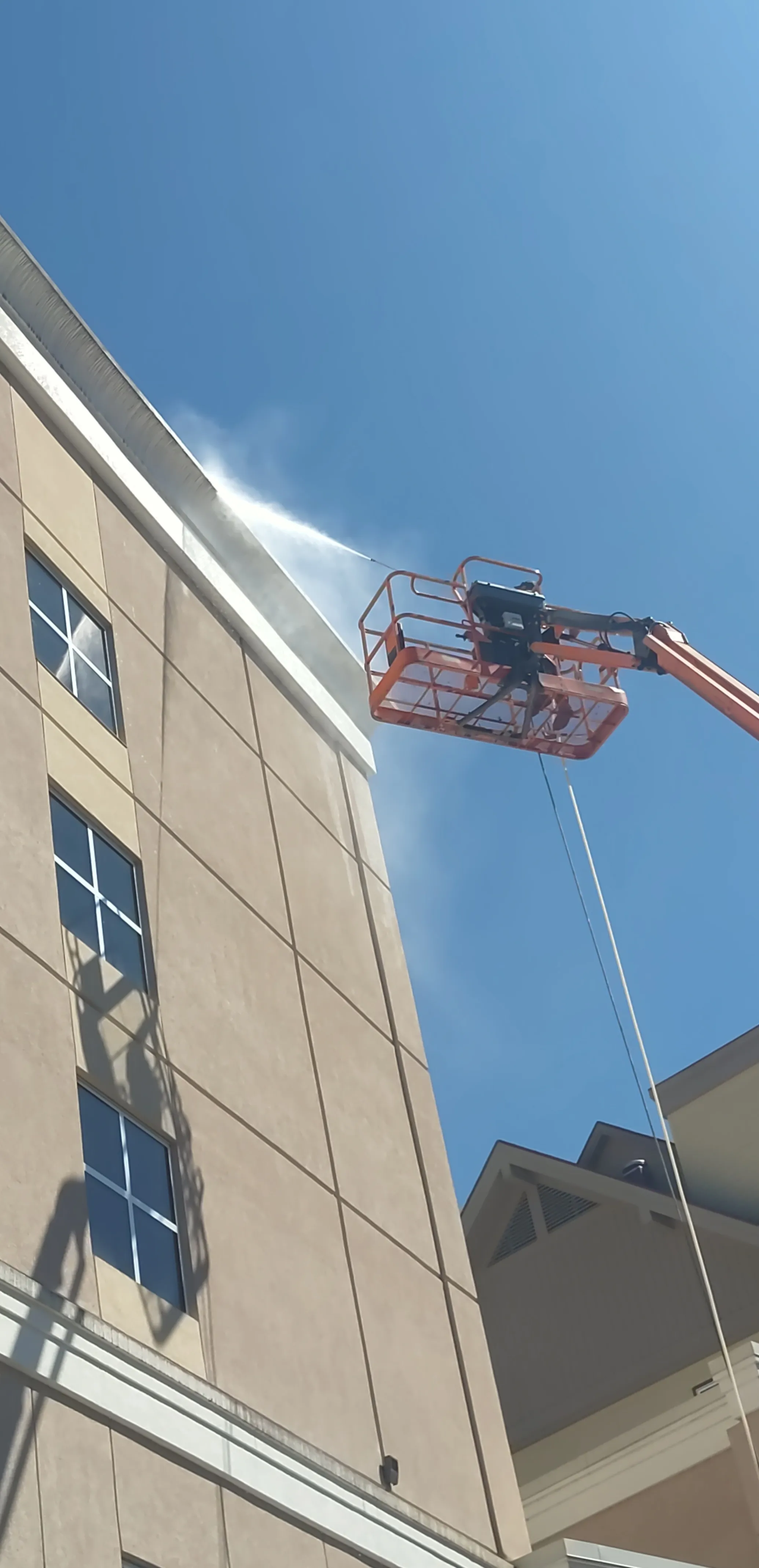 Lift crew performing commercial pressure washing using pressure washing services on building exterior in Knoxville TN