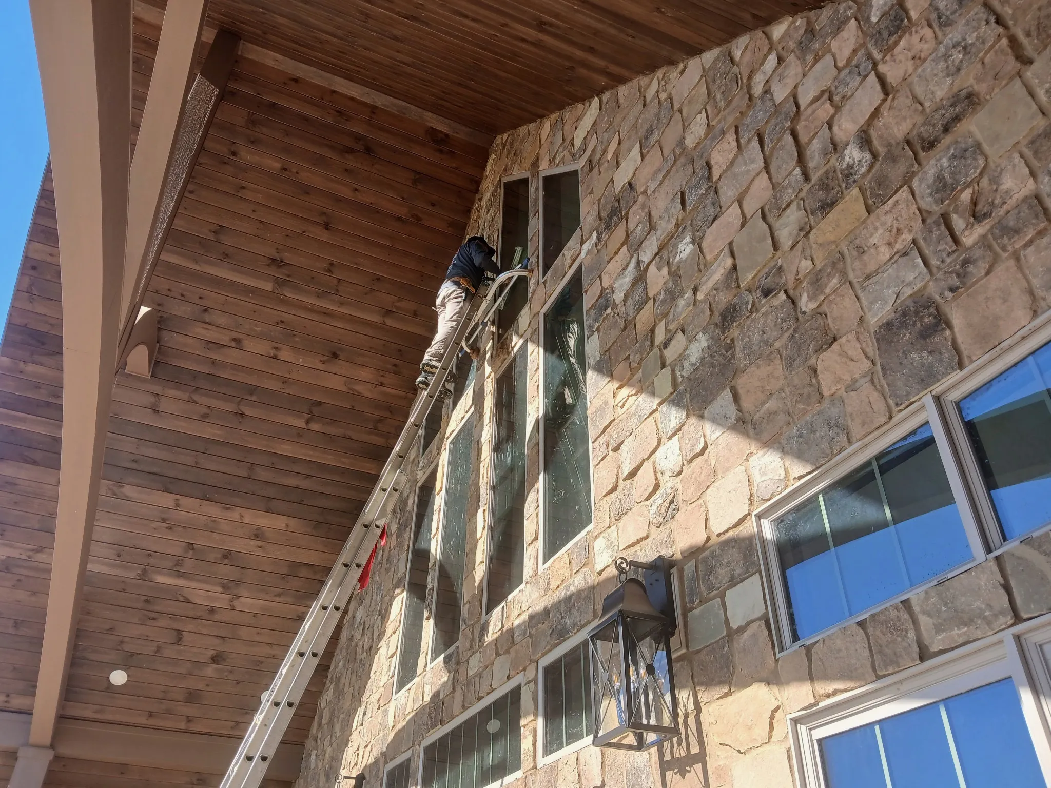 A technician using a professional squeegee to clean a large residential picture window.