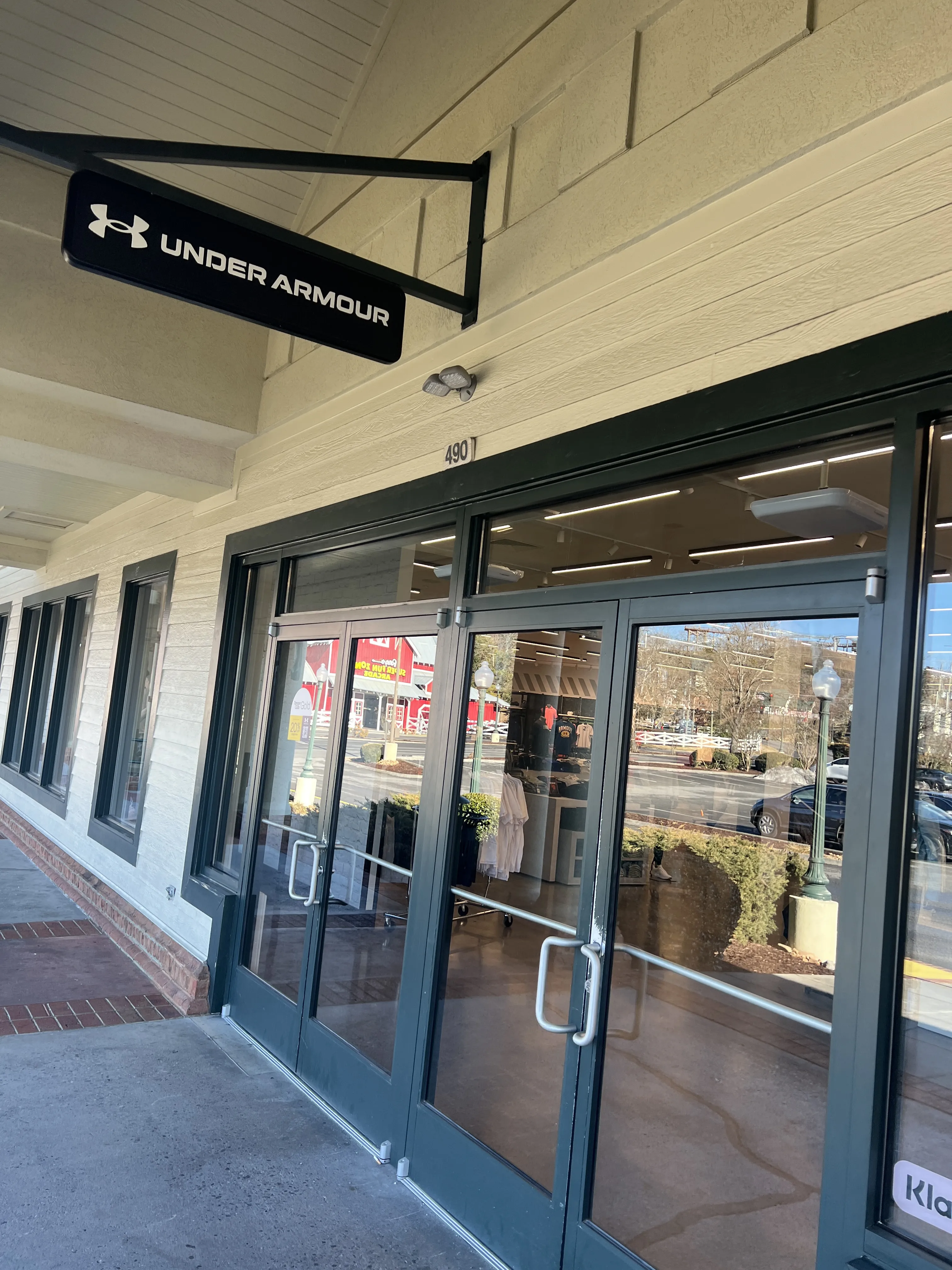 Glass storefront entrance with double doors and window reflections along a covered sidewalk