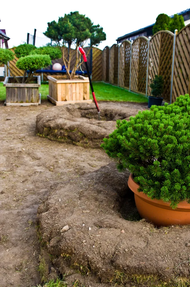 Custom stone retaining wall and matching circular fire pit area with a gravel walkway.