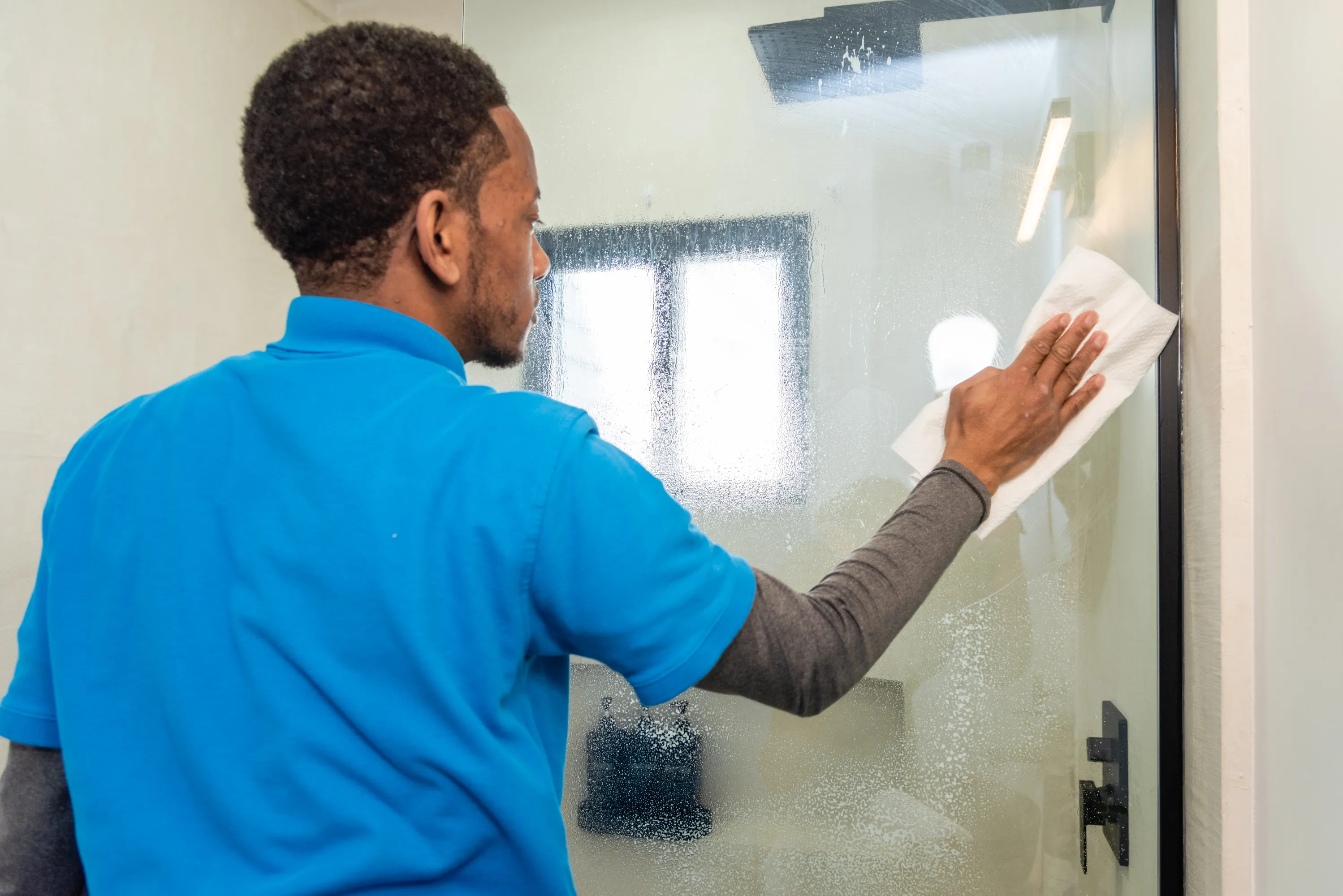 A professional cleaner wiping down a large glass window, revealing a clear view of Royal Oak’s.