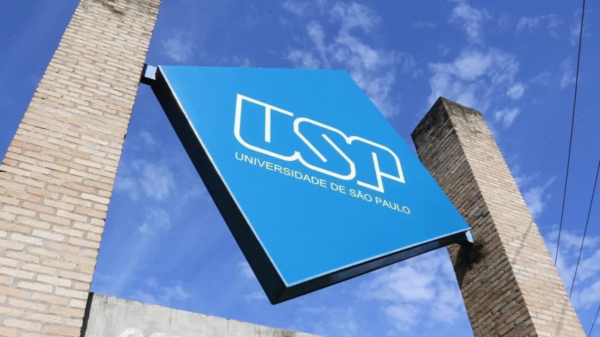 A Universidade de São Paulo (USP) se destacou como a segunda melhor da América Latina, conforme ranking internacional. Placa azul com 'USP UNIVERSIDADE DE SÃO PAULO' em branco, entre pilares de tijolos, céu